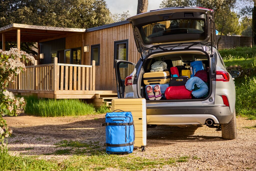 Kampeerplek waar een auto met een volle kofferbak met vakantiespullen