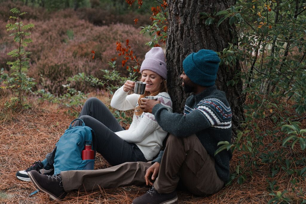 Een gezellig beeld van een man en vrouw die warme chocolademelk drinken onder een boom in de natuur