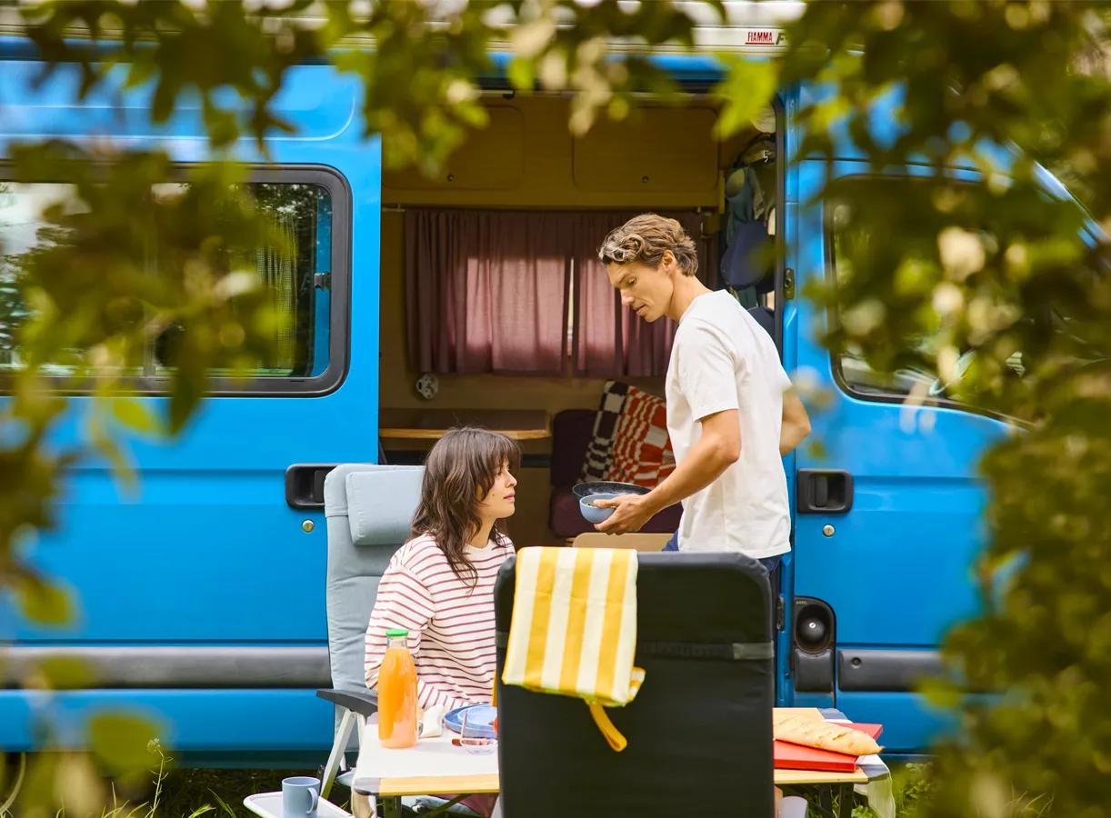 Een man en vrouw eten voor hun camper