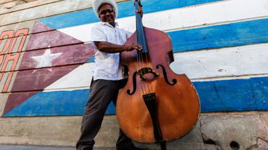 "Hispanic musician playing upright bass near Cuban flag, Santiago de Cuba, Santiago, Cuba"