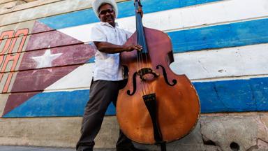 cuba_santiago-de-cuba_local_muzikant_vlag_straat_getty-565888951