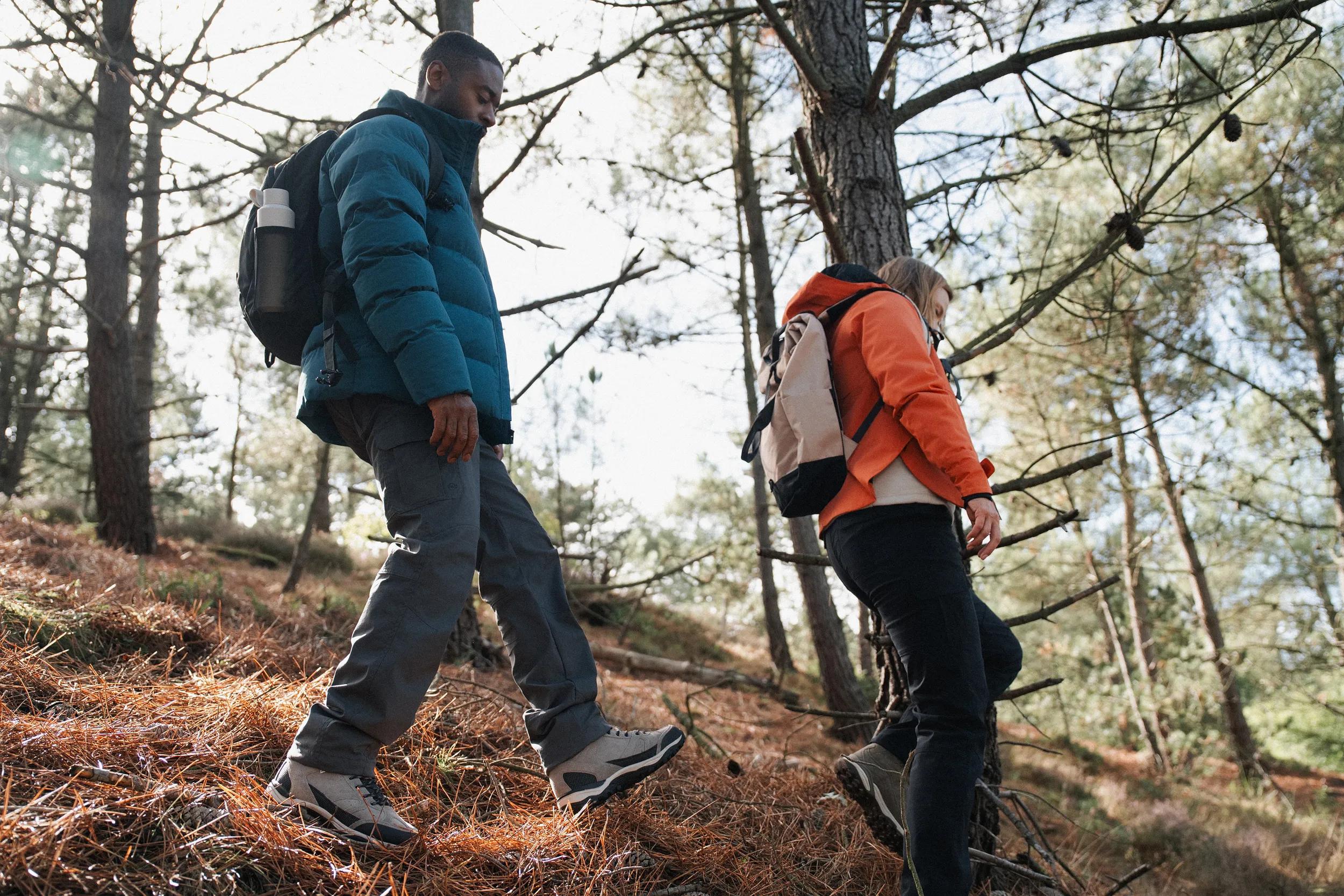 Twee mensen met een rugzak die aan het wandelen zijn in het bos