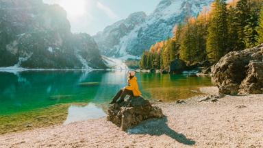 Young Caucasian woman  sitting on the background of  Lago di Braies in winter