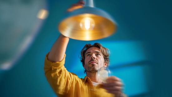 Man in gele trui zet plafondlamp aan