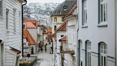 noorwegen_vestland_bergen_bryggen_winter_sneeuw_gebergte_straatje_mensen_unsplash