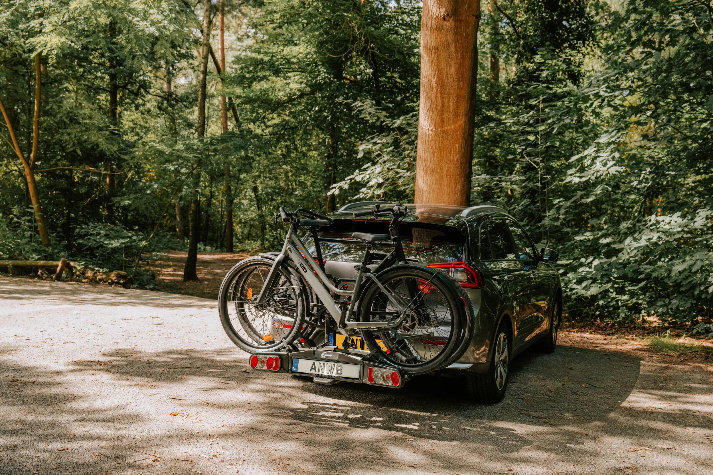 Fietsendrager achterop de auto in een bosrijke omgeving