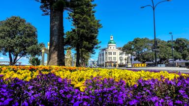 nieuw-zeeland_noordereiland_napier_koepel_gele-bloemen_paarse-bloemen_bomen_blauwe-lucht_true-art-deco-style-gebouw_shutterstock