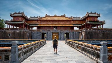 Young man at the gates of the imperial city of Hue, Vietnam. Tourist in Hue, Vietnam. Ancient stone gate of the imperial city of Hue, Vietnam. Happy tourist in Vietnam. Old gate of the imperial city of Hue.  Famous entrance to the imperial city of Hue, Vietnam