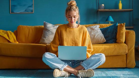 Vrouw in gele trui zit op haar laptop