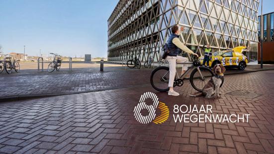 Man op de fiets zwaait vrolijk naar de Wegenwacht die hem net heeft geholpen.