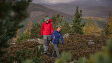 Two hillwalkers and their dogs enjoy the Braemar countryside, The Cairngorms National Park.