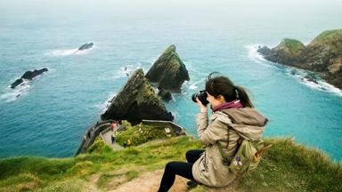 ierland_kerry_dingle_vrouw_meisje_camera_klif_zee_fotograferen_GettyImages-1147757682