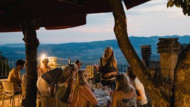 Large group of people enjoying an Italian meal together on top of a rooftop restaurant.