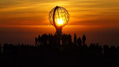 noorwegen_algemeen_noordkaap_globe_wereldbol_zonsondergang_avondrood_toerist_silhouet_getty