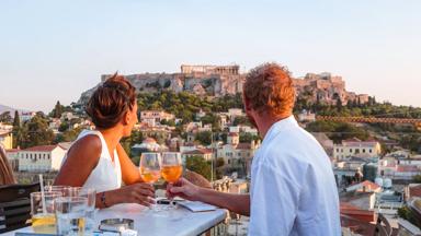 Couple drinking and enjoying the view of the Acropolis at sunset. Athens, Greece