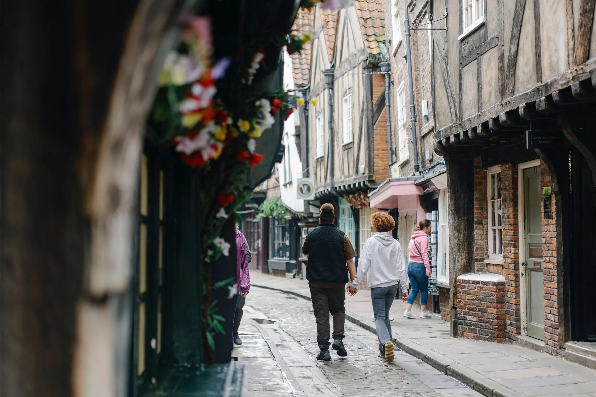 A man and woman holding hands on the Shambles, York
