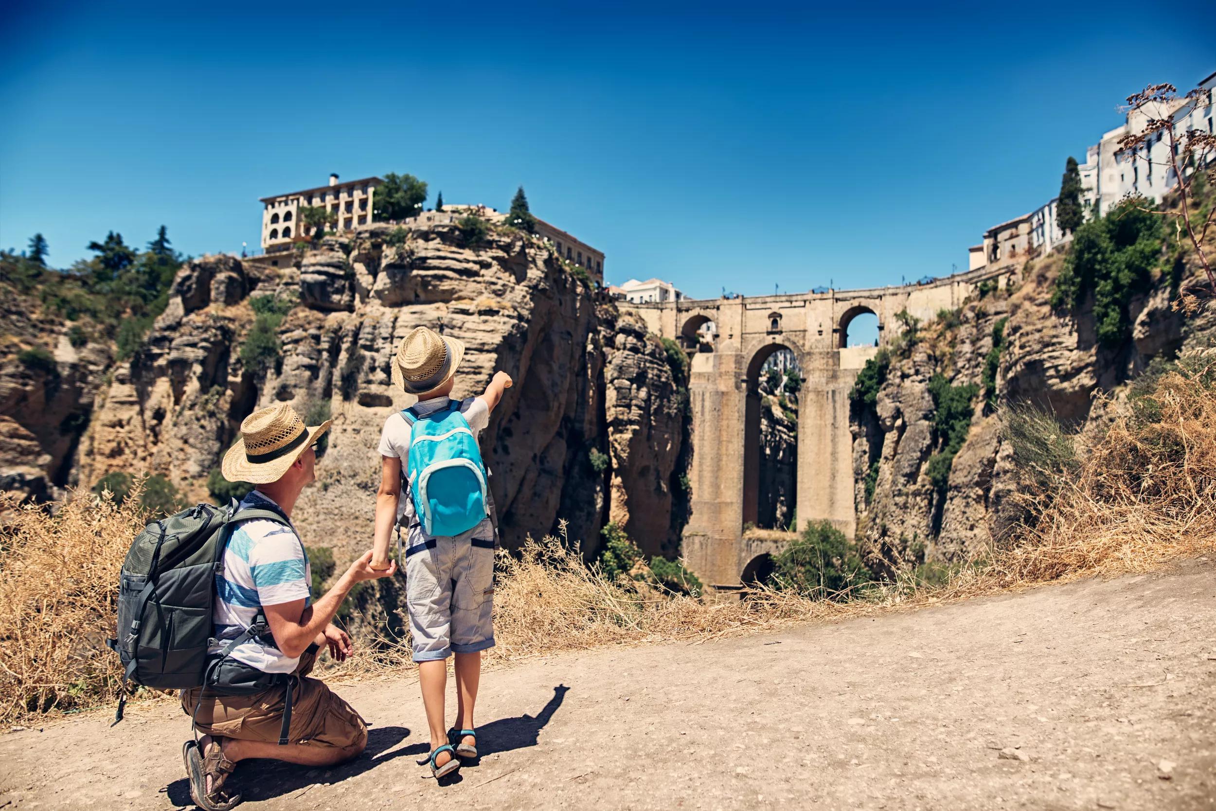 Fother and son visiting Ronda in Andalusia, Spain. They are looking at the famous Puente Nuevo bridge...