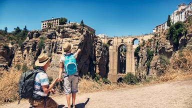 Fother and son visiting Ronda in Andalusia, Spain. They are looking at the famous Puente Nuevo bridge...