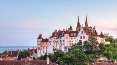 zwitserland_west-zwitserland_neuchatel_kasteel-neuchatel_zonsondergang_huizen_skyline_meer_bomen_shutterstock