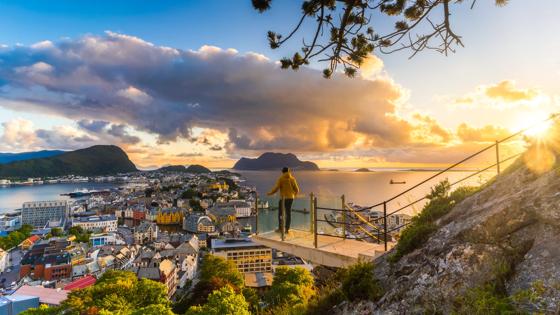 noorwegen_more-og-romsdal_alesund_byrampen-uitkijkpunt_zonsondergang_man_uitzichtpunt_zee_stad_getty-1173568843