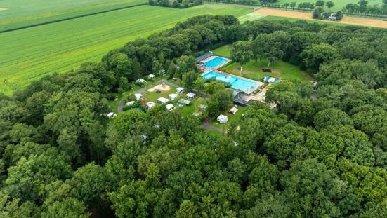 Luchtfoto van camping Zwinderen met staanplaatsen, veel bos en een zwembad.