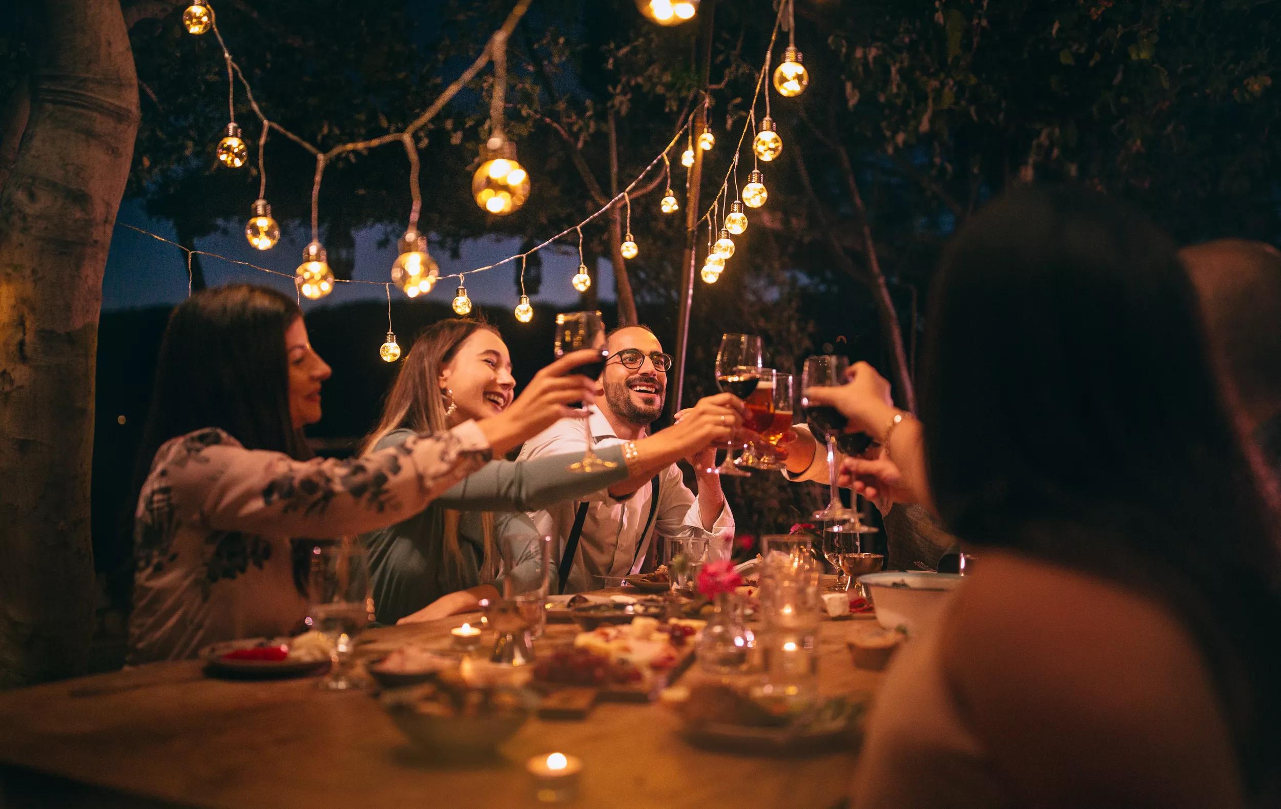 Happy young friends having fun and toasting around mediterranean dinner party table in Italian countryside