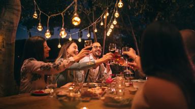 Happy young friends having fun and toasting around mediterranean dinner party table in Italian countryside