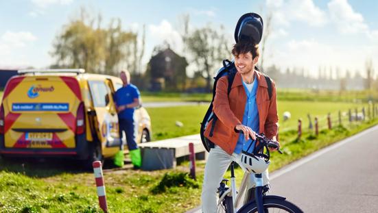 Jonge man op de fiets kijkt vrolijk. De Wegenwacht heeft hem net geholpen.