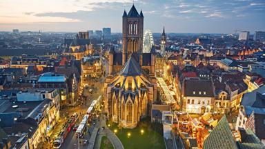 Aerial view of the medieval St Nicholas Church and skyline of Ghent with Christmas markets at dusk