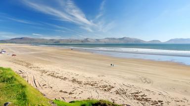 ierland_kerry_dingle-schiereiland_inch-beach_zandstrand_duingras_zee_bergketen_surfer_surfstrand_wandelaar_auto_shutterstock