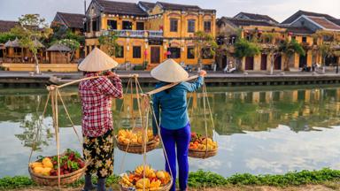 Vietnamese women selling tropical fruits, old town in Hoi An city, Vietnam. Hoi An is situated on the east coast of Vietnam. Its old town is a UNESCO World Heritage Site because of its historical buildings.