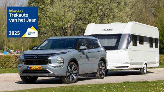 Grijze Mitsubishi Outlander PHEV met caravan aan de haak.