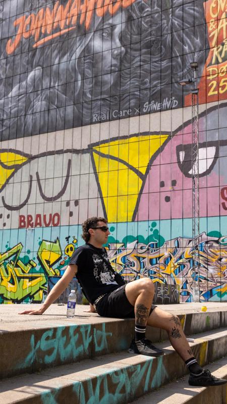Man op trap in Norrebro met street-art op de muur erachter. Kopenhagen