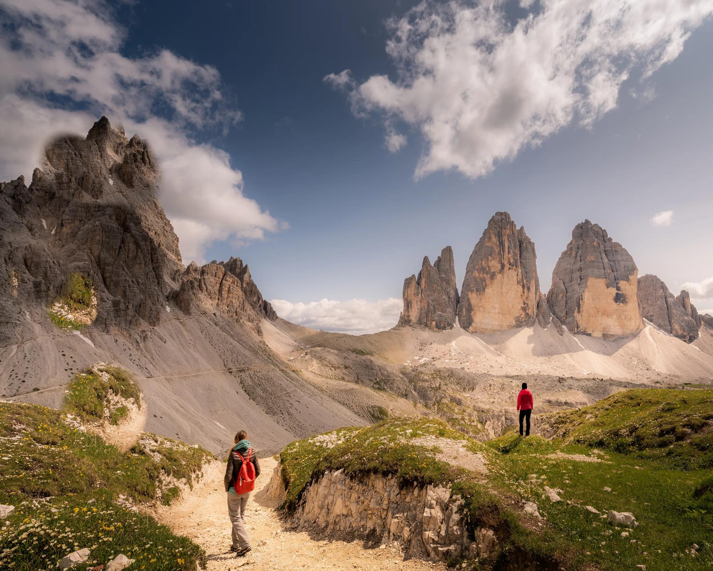 Two women hiking at Tre Cime di Lavaredo, Dolomites Alps, Italy. Blue Sky, wildflowers.