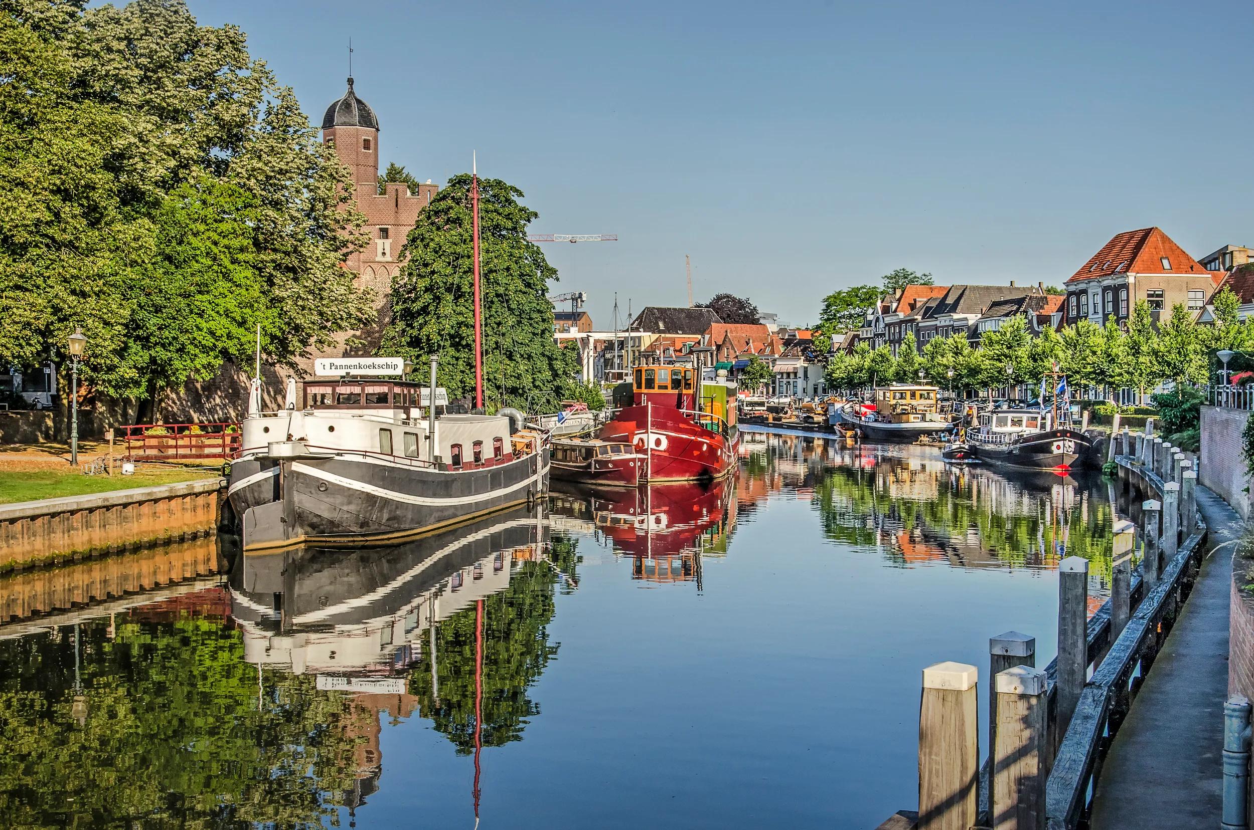 Zwolle; The Netherlands; July 24; 2019: colorful historic vessels in and houses around Thorbecke canal on a sunny and windless summer morning