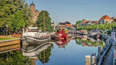 Zwolle; The Netherlands; July 24; 2019: colorful historic vessels in and houses around Thorbecke canal on a sunny and windless summer morning