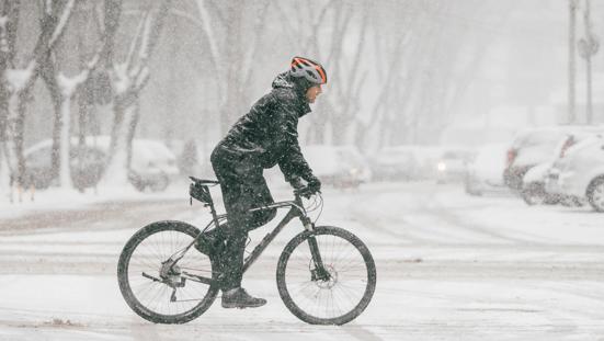 Man fiets in sneeuwbui door de stad.