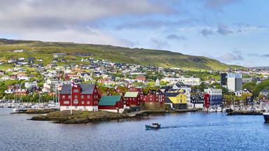 Denmark, Torshavn. July 12th, 2018. Tórshavn, the capital and largest city of the Faroe Islands, is located in the southern part on the east coast of Streymoy. Tinganes is the historic location and the central part of Tórshavn. Many of the wooden houses on Tinganes were built in the 16th and 17th centuries and have the typical red color as well as grass roof, that is very common on the Faroe Islands.