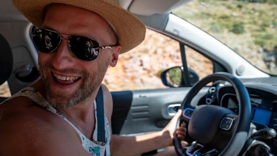 Zomers geklede man met zonnebril in auto.