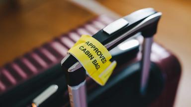 Approved cabin bag label attached to a handle of a suitcase