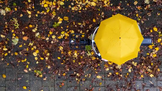 Fietser met gele paraplu fiets in de regen, van boven gezien.