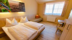 Doppelbett im Doppelzimmer im JUFA Hotel Neutal Landerlebnis mit Wandbild. Der Ort für erlebnisreichen Natururlaub für die ganze Familie.
