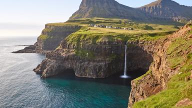 Waterfall and cliffs on Vagar. Faroe Islands dramatic coastline. Gasaladur