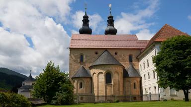 Sie sehen eine Aussenansicht vom JUFA Hotel Stift Gurk mit Dom im Sommer. JUFA Hotels bietet Ihnen den Ort für erlebnisreichen Natururlaub für die ganze Familie.