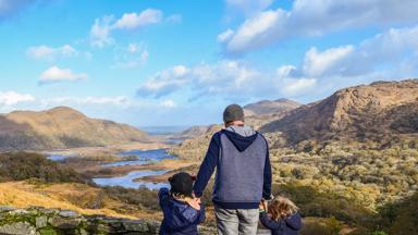 Father with two young children overlook a scenic valeey in Ire3land along the Ring of Kerry