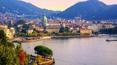 Como city historical town center and Alps mountains on Lake Como, Italy, in warm sunset light