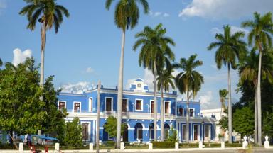 cuba_cienfuegos_cienfuegos_aduana_douane_blauw-gebouw_palmbomen_fiets_w