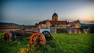 Sie sehen eine Außenansicht vom JUFA Hotel Kronach – Festung Rosenberg bei Abenddämmerung im Sommer. JUFA Hotels bietet kinderfreundlichen und erlebnisreichen Urlaub für die ganze Familie.