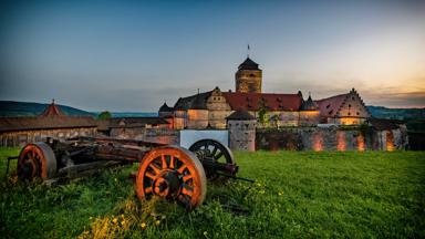 Sie sehen eine Außenansicht vom JUFA Hotel Kronach – Festung Rosenberg bei Abenddämmerung im Sommer. JUFA Hotels bietet kinderfreundlichen und erlebnisreichen Urlaub für die ganze Familie.