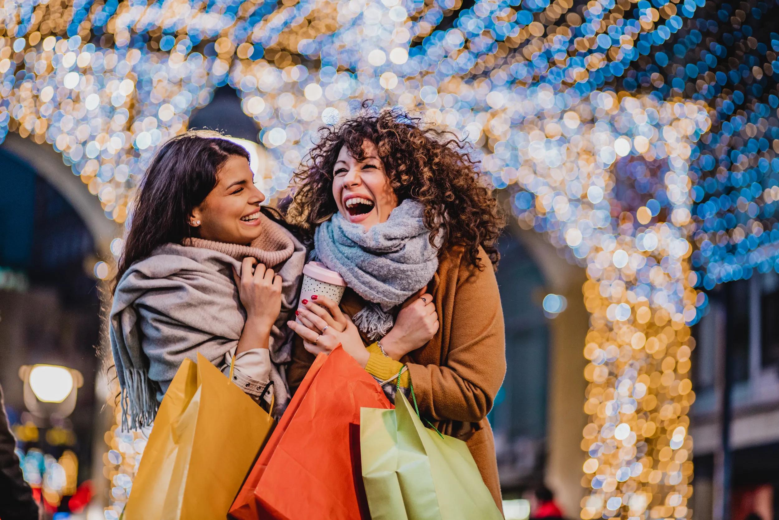 Two female friends are outdoors holding shopping bags